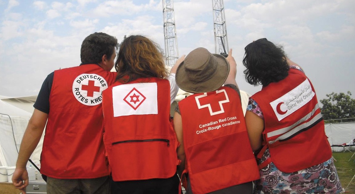 A group of four Red Cross people wearing vests from their different home countries