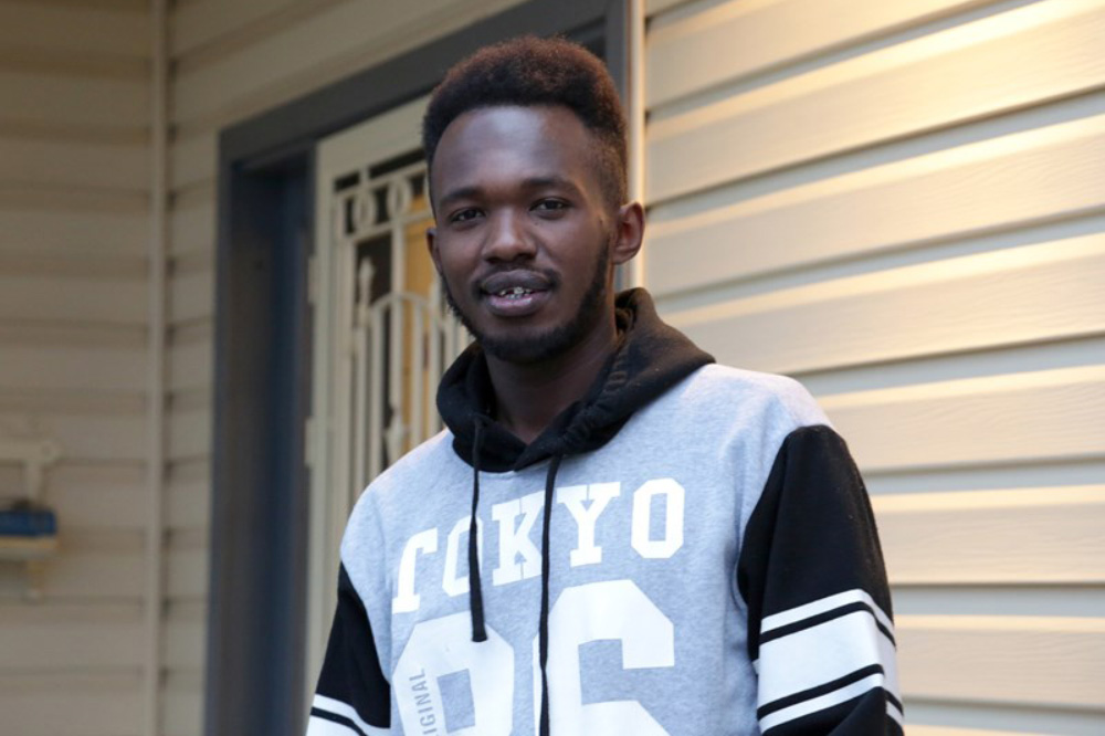 A young man, Elie, smiles in a portait photo.