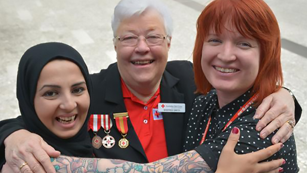 Three women, all Members od Red Cross, smile in a group photo