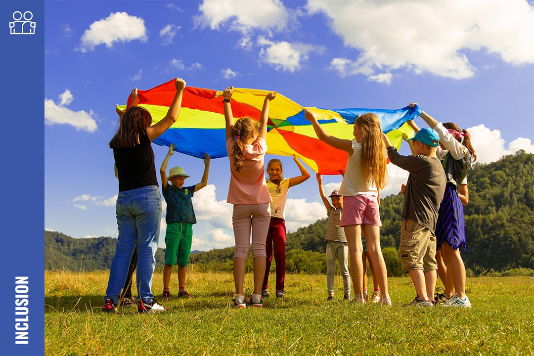 Children playing with a large rainbow-coloured flag