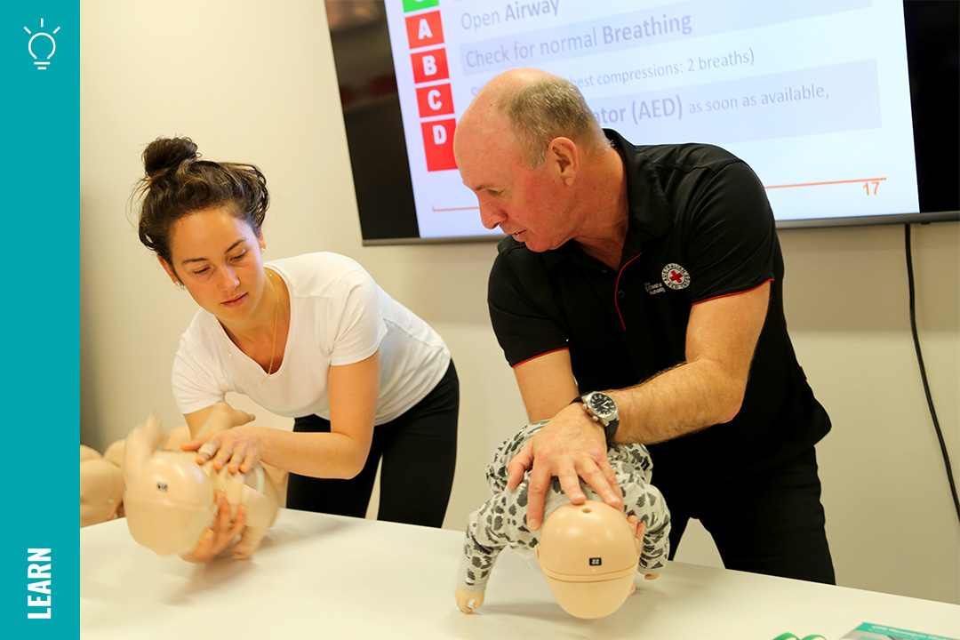 A man and a woman with First Aid training mannequins of babies