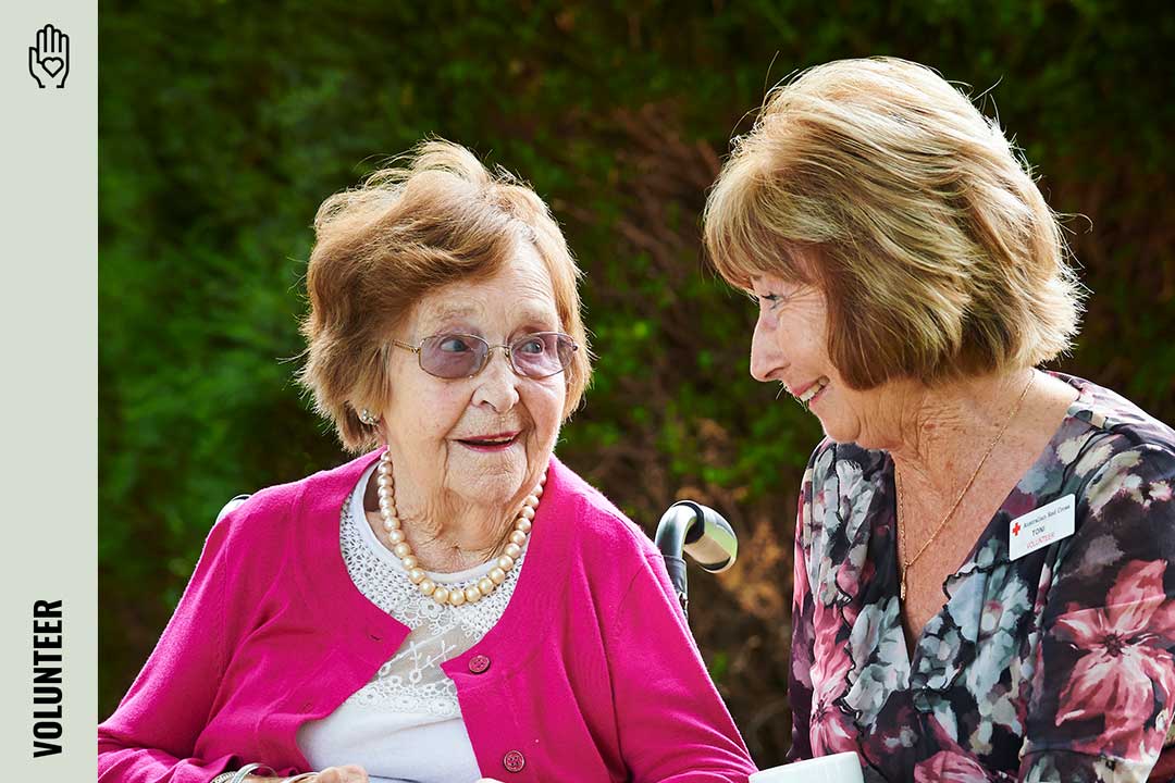 Red Cross volunteer sitting with an eldery person