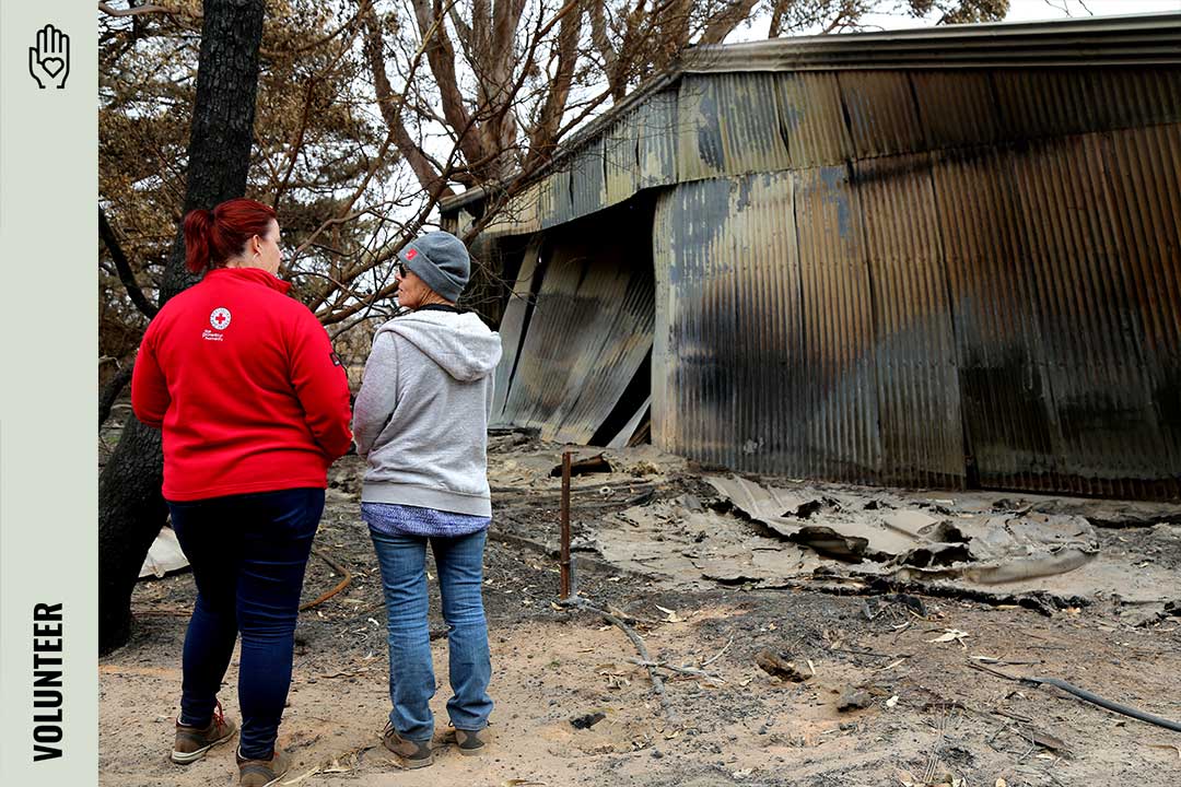 Two people standing in front of a burnt shed