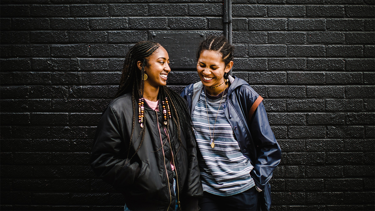 Two smiling people in front of a wall