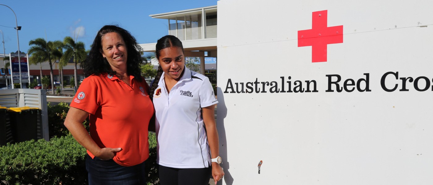 Two women in front of a Red Cross sign